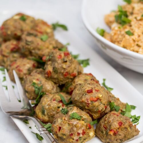 A platter of Tex-Mex Meatballs with a bowl of Mexican Cauliflower Rice in the background.