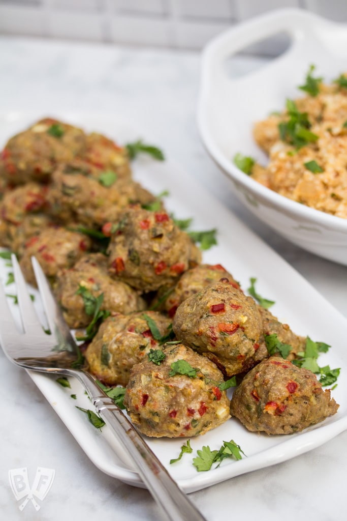 A platter of Tex-Mex Meatballs with a bowl of Mexican Cauliflower Rice in the background.