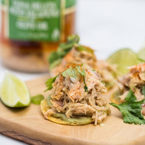 Mini tuna tostadas on a platter with lime and cilantro.