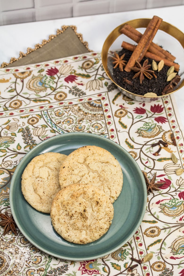 Overhead view of a plate of Chai Spiced Snickerdoodle Cookies with a bowl of whole spices in the background.