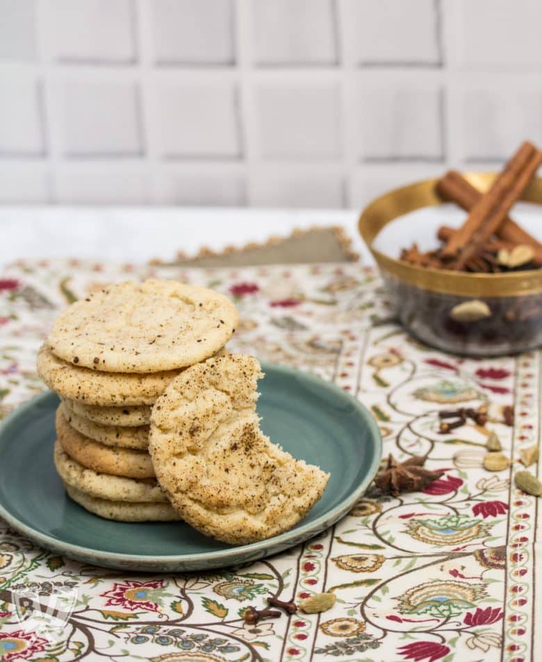 3/4 view of a plate of Chai Spiced Snickerdoodle Cookies with a bowl of whole spices in the background.
