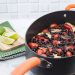 3/4 view up of a Latin Chicken Skillet with Black Beans + Tomatoes with a cutting board and limes off to the side.
