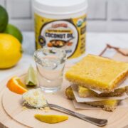 A stack of dessert bars with a shot of tequila, fresh citrus, and a jar of butter flavored coconut oil.