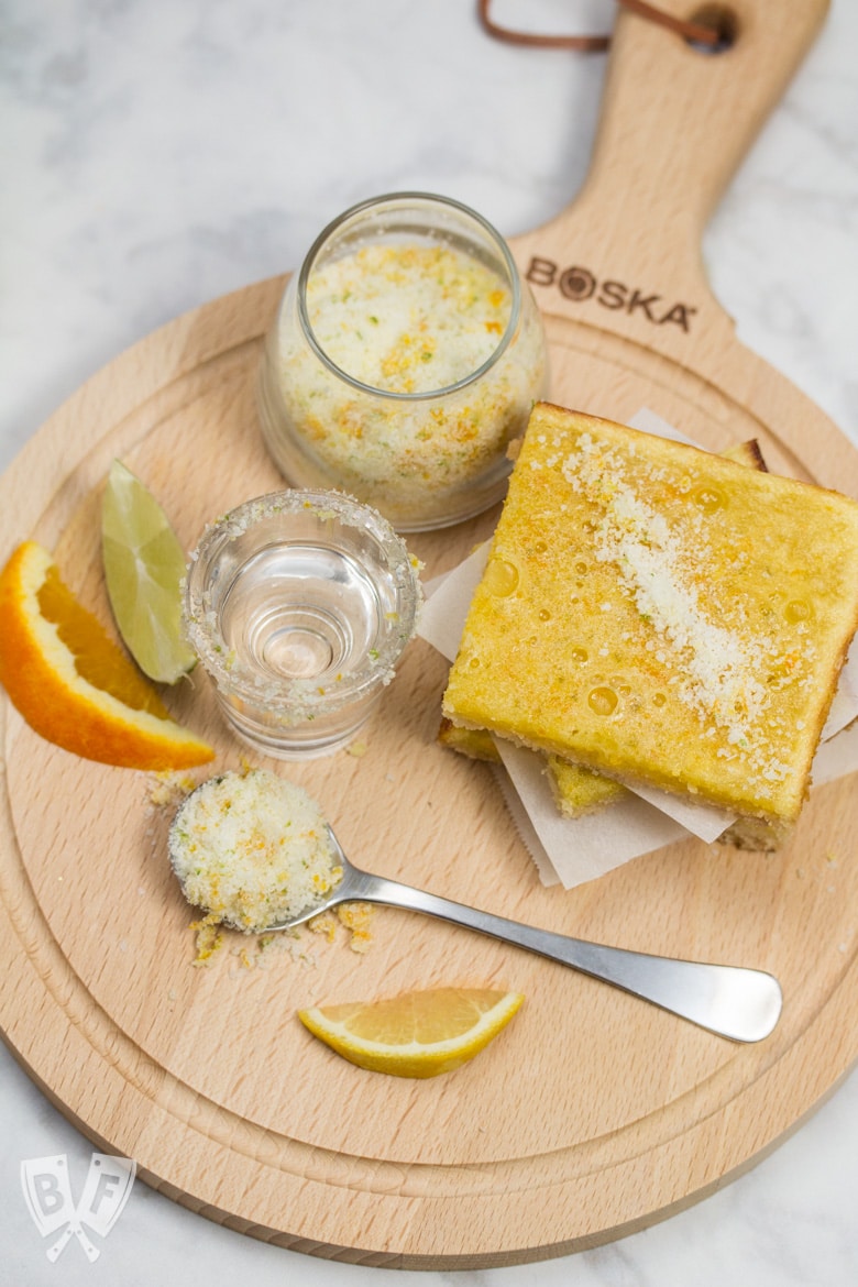 Overhead view of a stack of dessert bars with a shot of tequila, and fresh citrus.