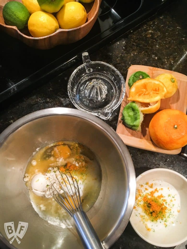 Overhead view of mixing bowls and a juicer with fresh oranges, lemons, and limes.