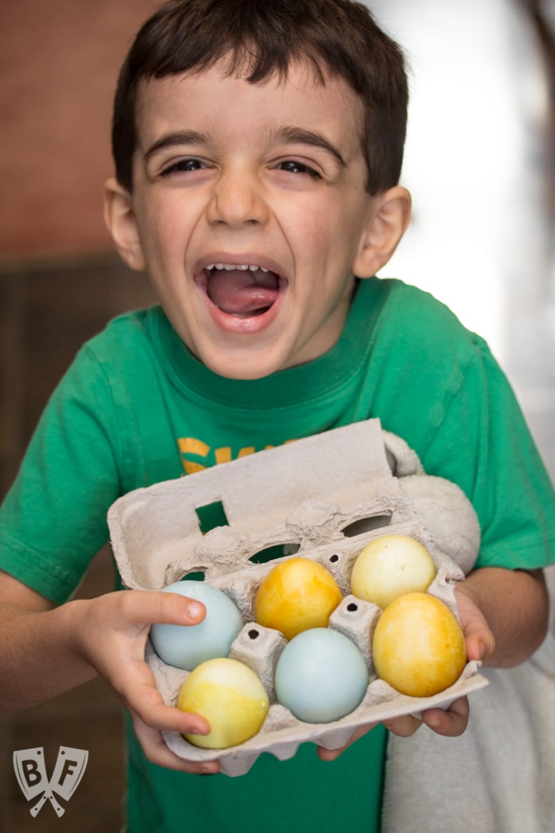 A boy holding a carton of naturally dyed Easter eggs.