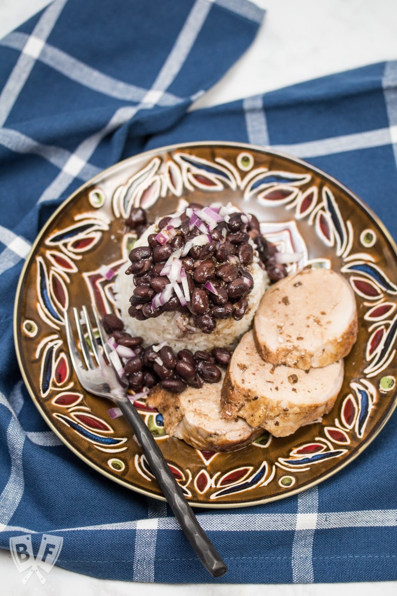 Overhead view of a plate of sliced pork tenderloin served with rice and beans