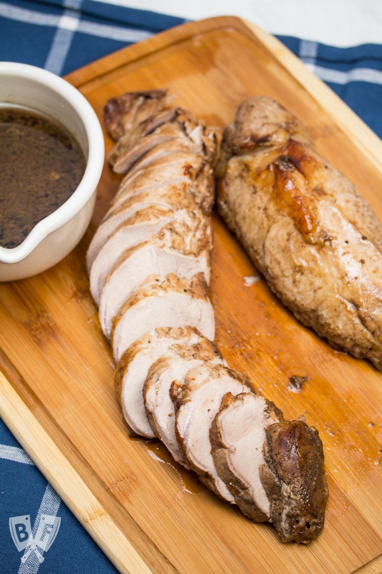 Overhead view Balsamic Marinated Pork Tenderloin esculpido em uma tábua de corte.