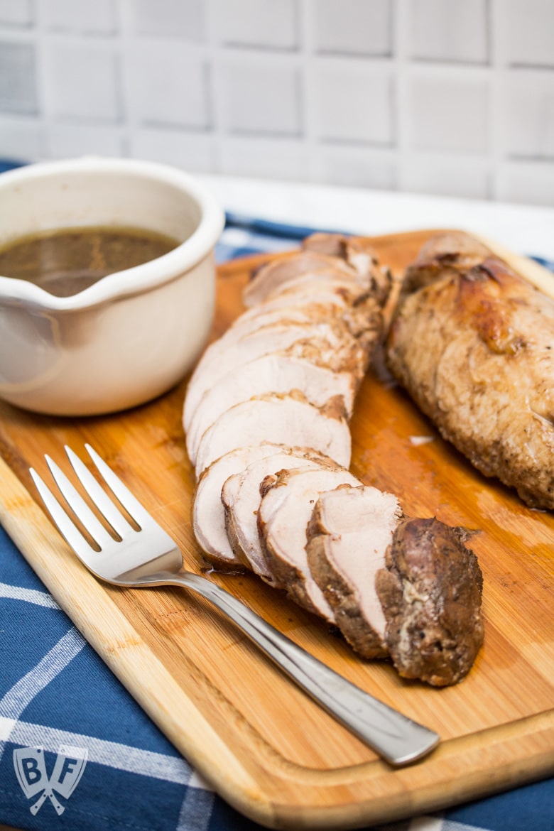 ¾ view Balsamic Marinated Pork Tenderloin carved on a cutting board.