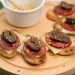 Honeyed Chorizo & Fig Crostini displayed on a board with a honey dipper.
