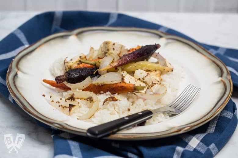 ¾ view of a plate of rice topped with roasted tofu, onions, and rainbow carrots.