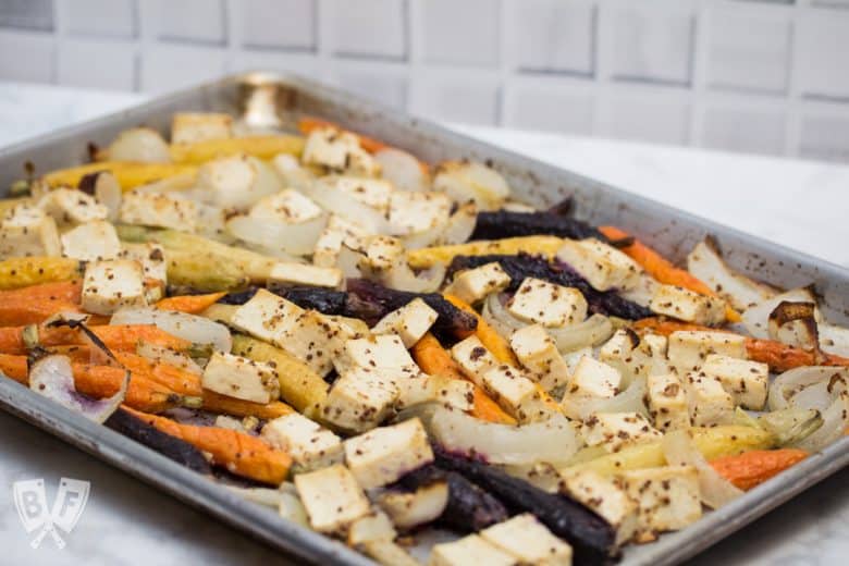 ¾ view of a sheet pan with roasted tofu, onions, and rainbow carrots.