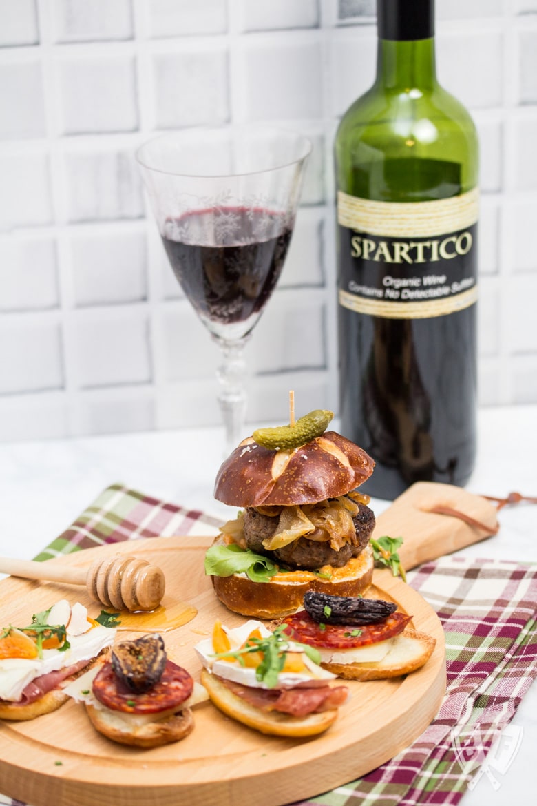 ¾ view of a board with an assortment of Spanish tapas with wine in the background.