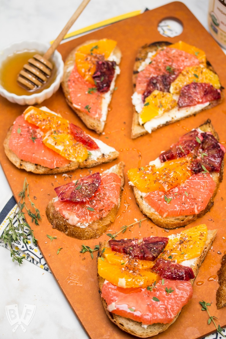 Overhead view of a board full of Goat Cheese Toast with Honeyed Citrus Fruit.