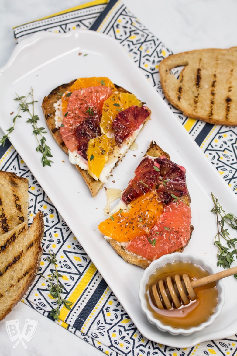 Overhead view of Goat Cheese Toast with Honeyed Citrus Fruit and ingredients around the sides.