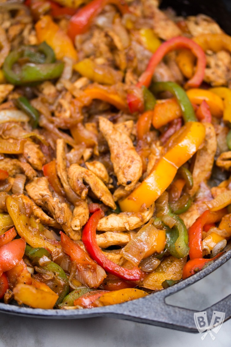 Close up of chicken fajitas in a cast iron skillet.