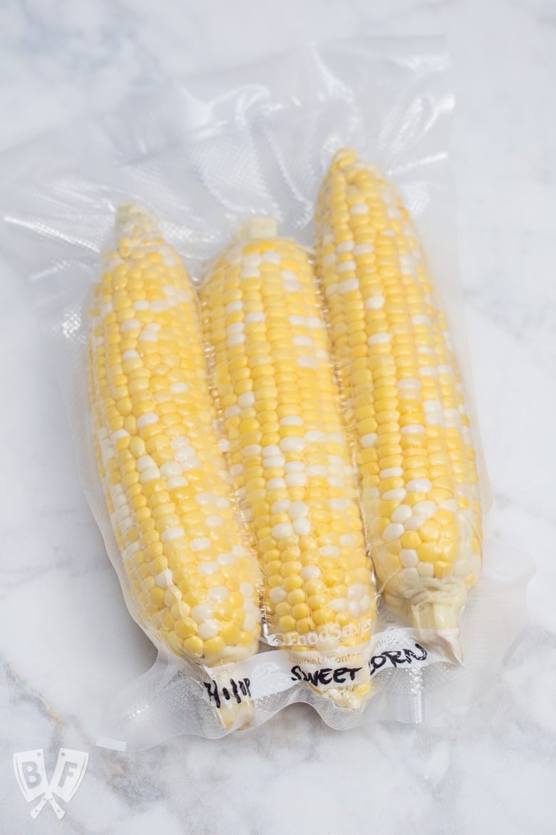 Overhead view of 3 ears of corn in a vacuum-sealed bag.