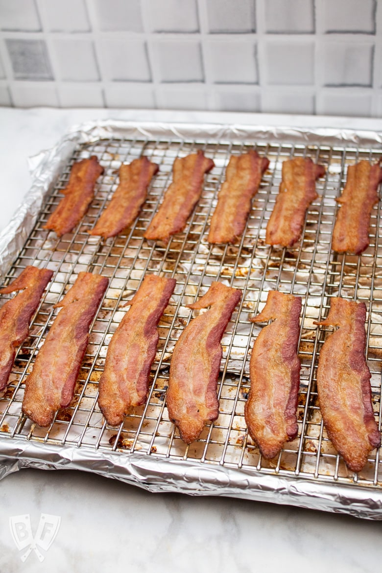 ¾ view of slices of cooked bacon on a foil-lined sheetpan.