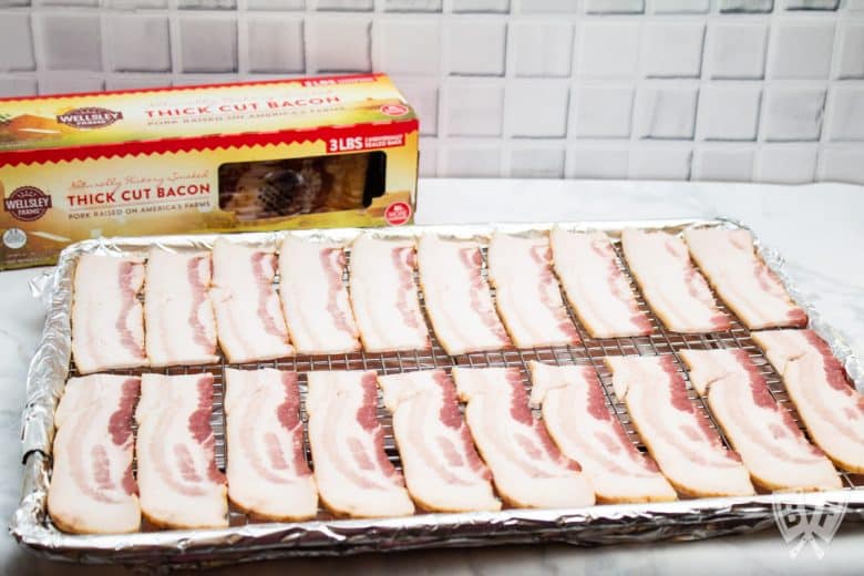 3/4 view of slices of bacon on a foil-lined sheetpan with the package in the background.