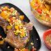Platter of Sous Vide Double Cut Pork Chops with Raw Summer Corn & Tomato Salad with gravy served alongside.