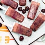 Overhead view of a tray of ice with Black Forest Popsicles and fresh cherries.