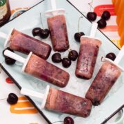 Overhead view of a tray of ice with Black Forest Popsicles and fresh cherries.