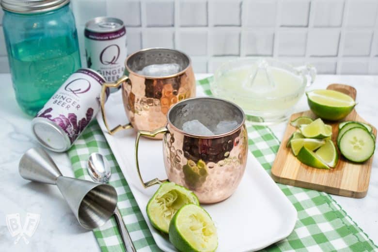 ¾ view of ingredients and copper mugs for making Cucumber Moscow Mule Cocktails.