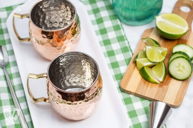 Overhead shot of ingredients and copper mugs for making Cucumber Moscow Mule Cocktails.