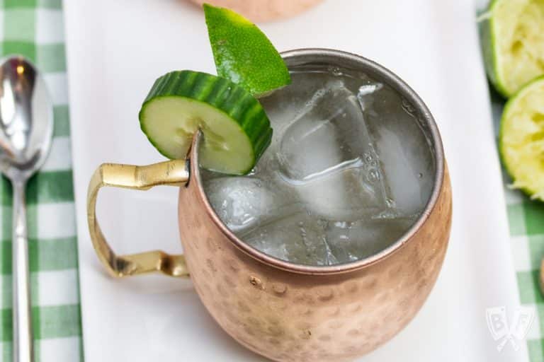 Overhead view of a copper mug filled with a Cucumber Moscow Mule cocktail with ingredients alongside.