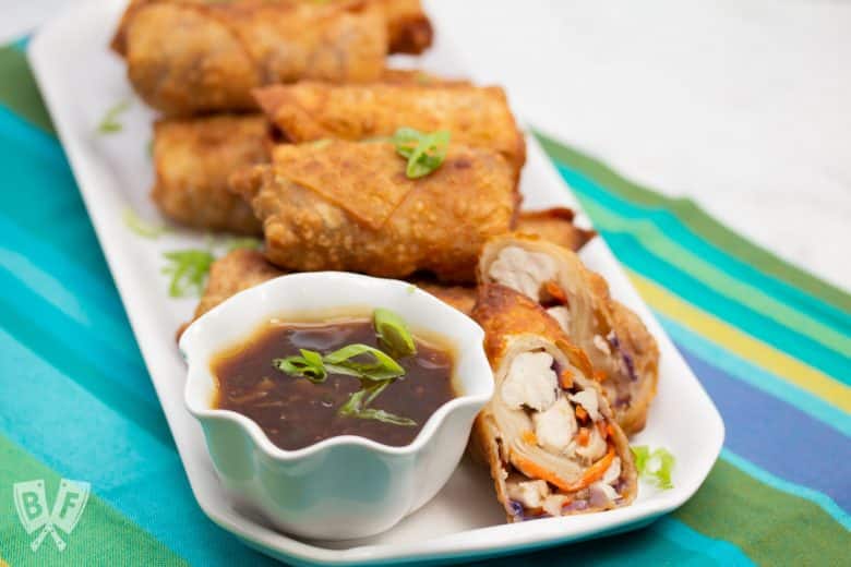 ¾ view of a platter of General Tsao’s Chicken Egg Rolls with a bowl of dipping sauce.