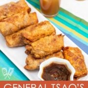 ¾ view of a platter of General Tsao’s Chicken Egg Rolls with a bowl of dipping sauce and glasses of iced tea.