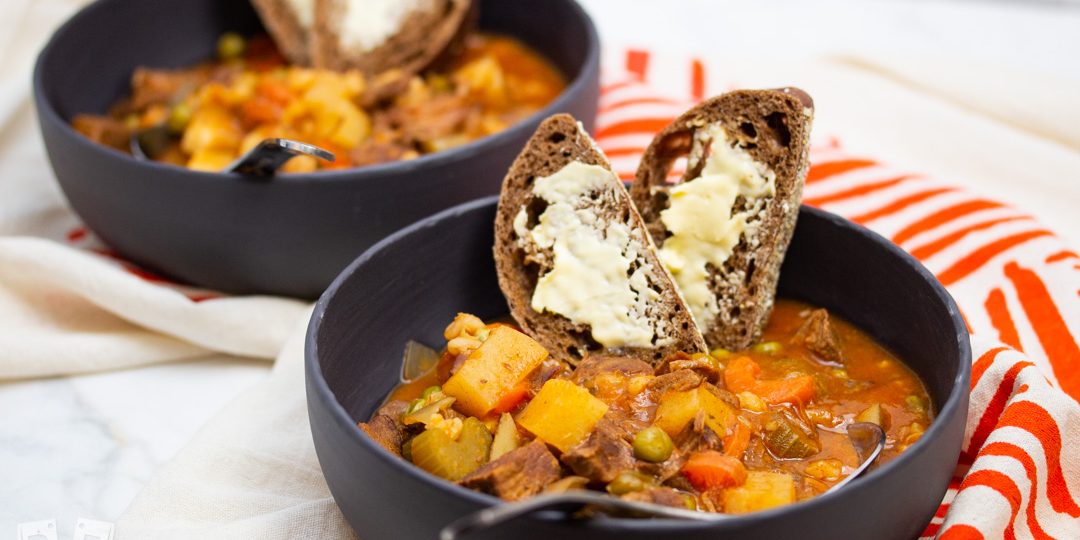 2 bowls of beef stew with bread and butter.