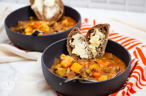 2 bowls of beef stew with bread and butter.
