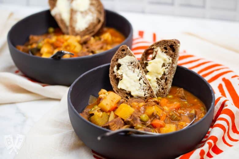 2 bowls of beef stew with bread and butter.