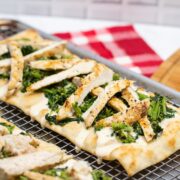 2 chicken and broccoli rabe pizzas sitting on a metal baking rack.