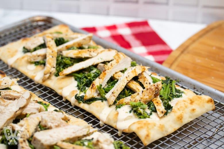 2 chicken and broccoli rabe pizzas sitting on a metal baking rack.