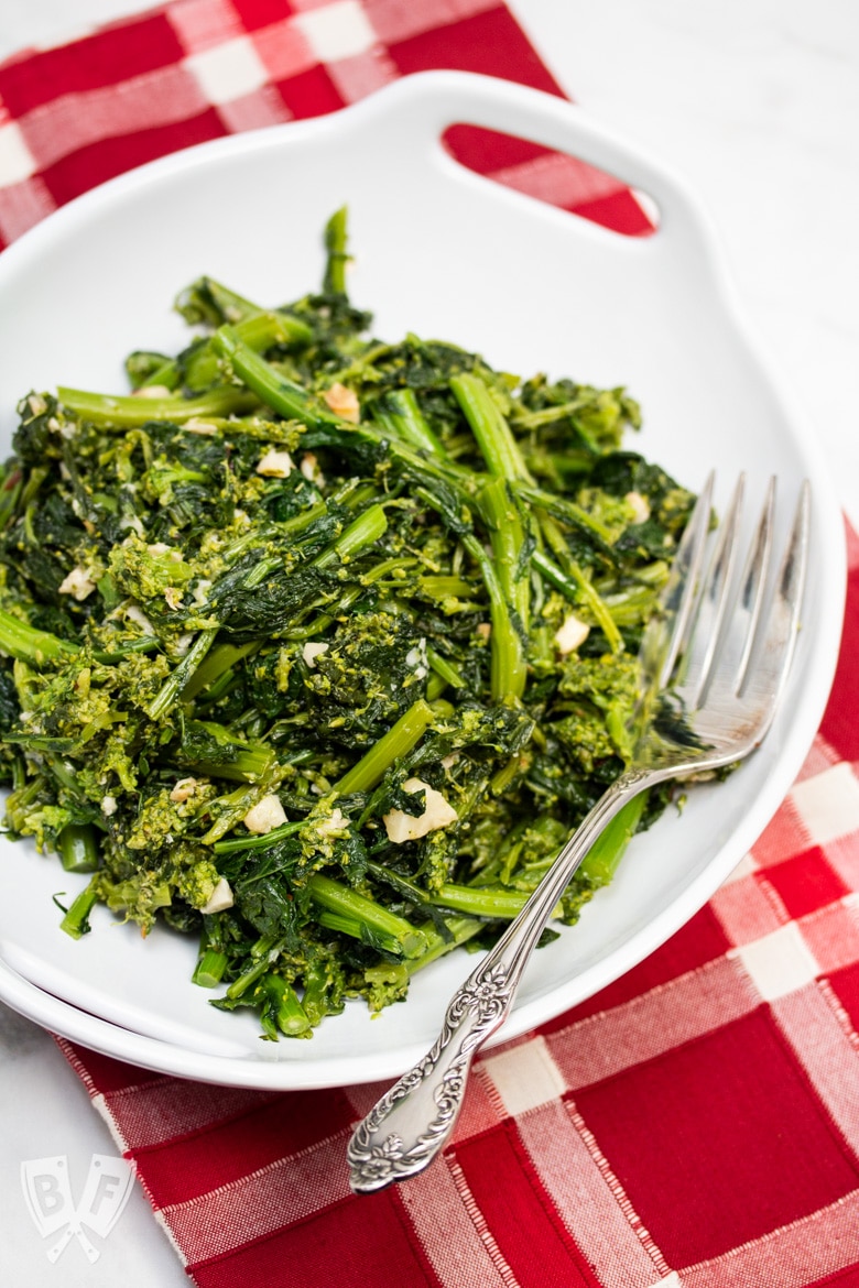 Overhead view of a bowl of broccoli rabe and garlic with a serving fork.