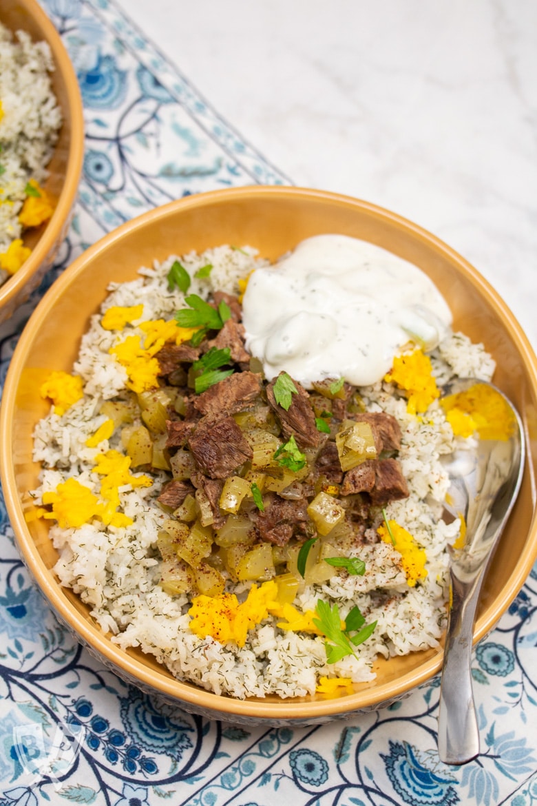 Overhead view of a bowl of Instant Pot Persian Beef and Celery Stew (Khoreshe Karafs) with mast-o-khiar over dill rice.