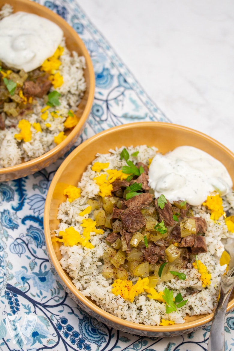 Overhead view of 2 bowls of Instant Pot Persian Beef and Celery Stew (Khoreshe Karafs) with mast-o-khiar over dill rice.