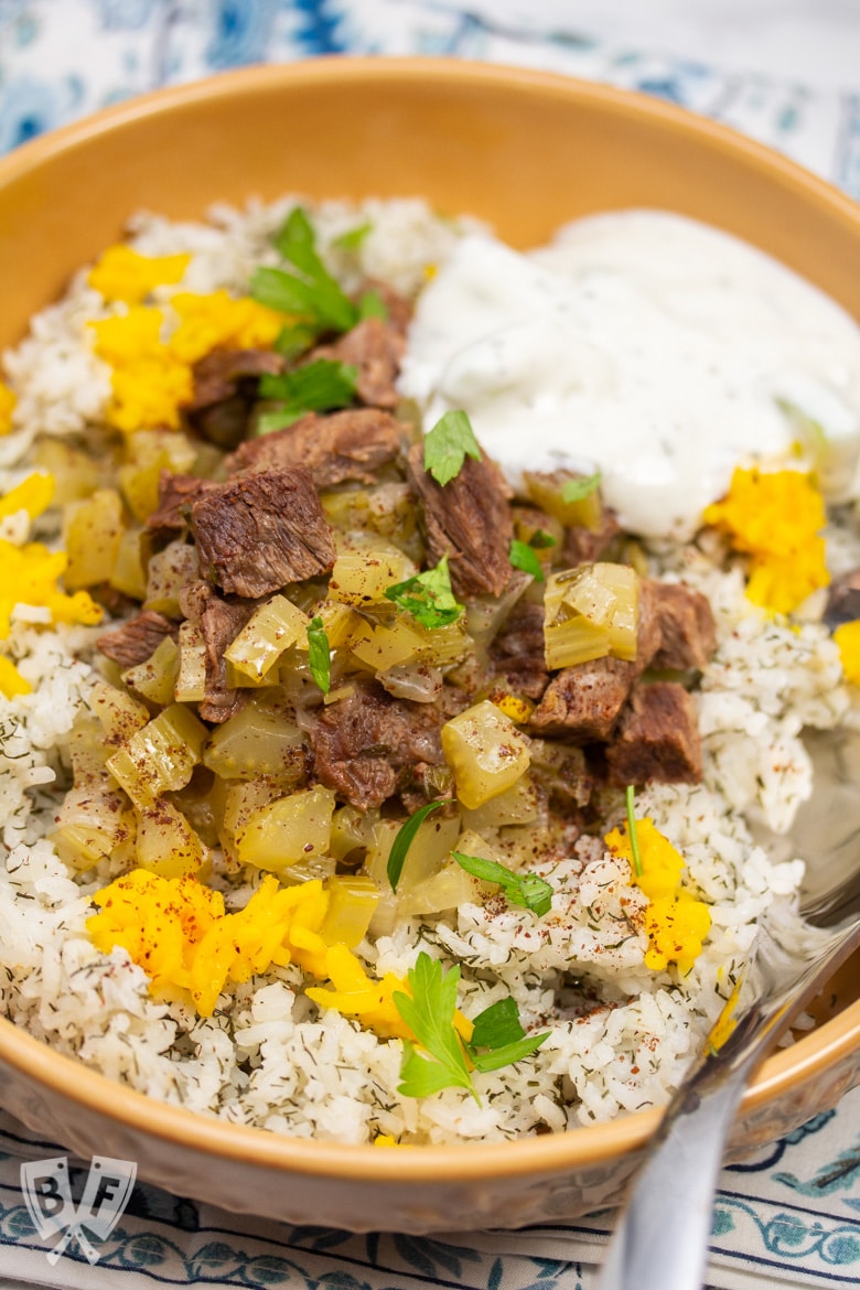 Overhead view of a bowl of Instant Pot Persian Beef and Celery Stew (Khoreshe Karafs) with mast-o-khiar over dill rice.