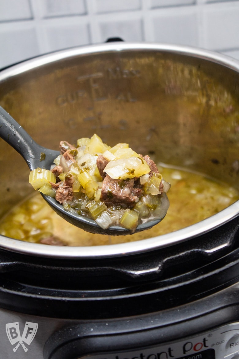 A ladle of Instant Pot Persian Beef and Celery Stew (Khoreshe Karafs) being lifted from the Instant Pot.