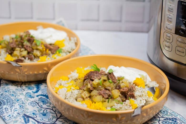 ¾ view of 2 bowls of Instant Pot Persian Beef and Celery Stew (Khoreshe Karafs) with mast-o-khiar over dill rice next to an Instant Pot.