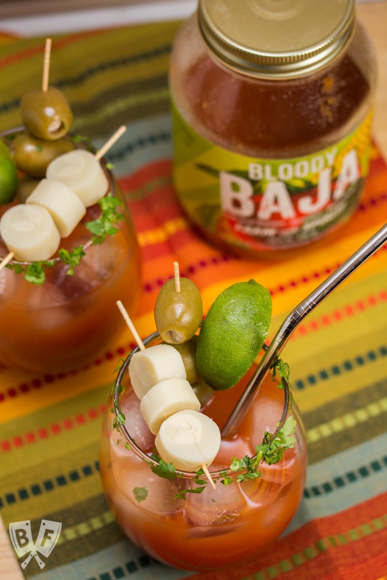 Overhead view of 2 bloody mary cocktails and the mixer jar in the background.