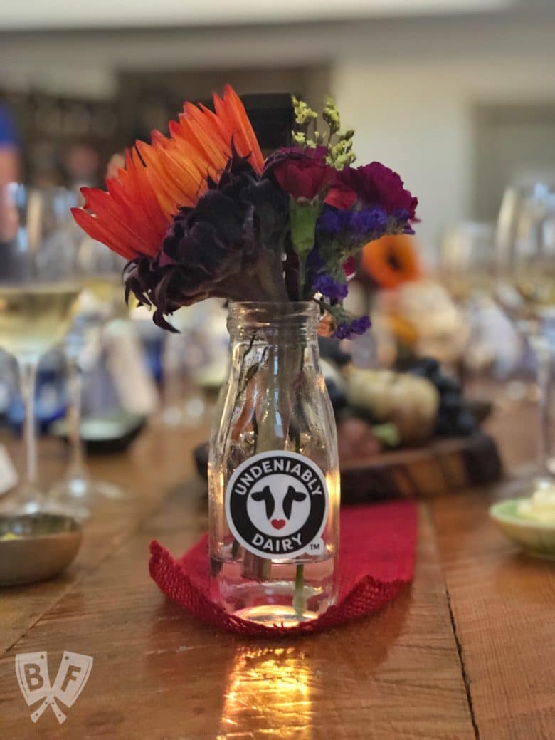 Milk jar full of flowers as a centerpiece for a farm-to-fork dinner.