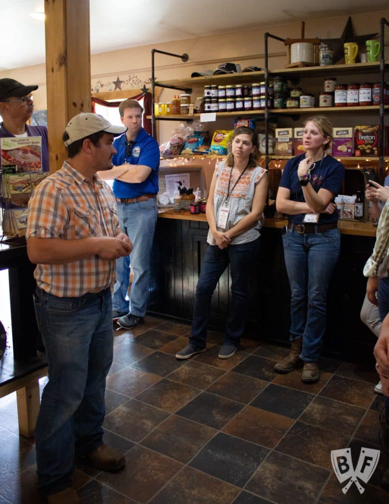 A farmer talking to a group of people inside the farm shop.