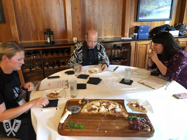 Judges sitting at a table eating a freshly-baked pizza.