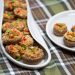 A platter full of Italian stuffed mushroom caps with an appetizer plate alongside..