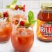 Side view of 3 Bloody Mary cocktails garnished with Italian antipasto ingredients next to a jar of Bloody Mary mix.