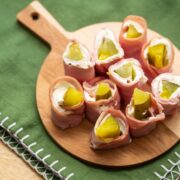 Overhead view of a round board full of pickle treat appetizers.