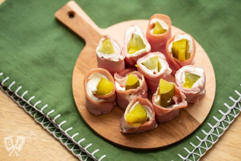 Overhead view of a round board full of pickle treat appetizers.